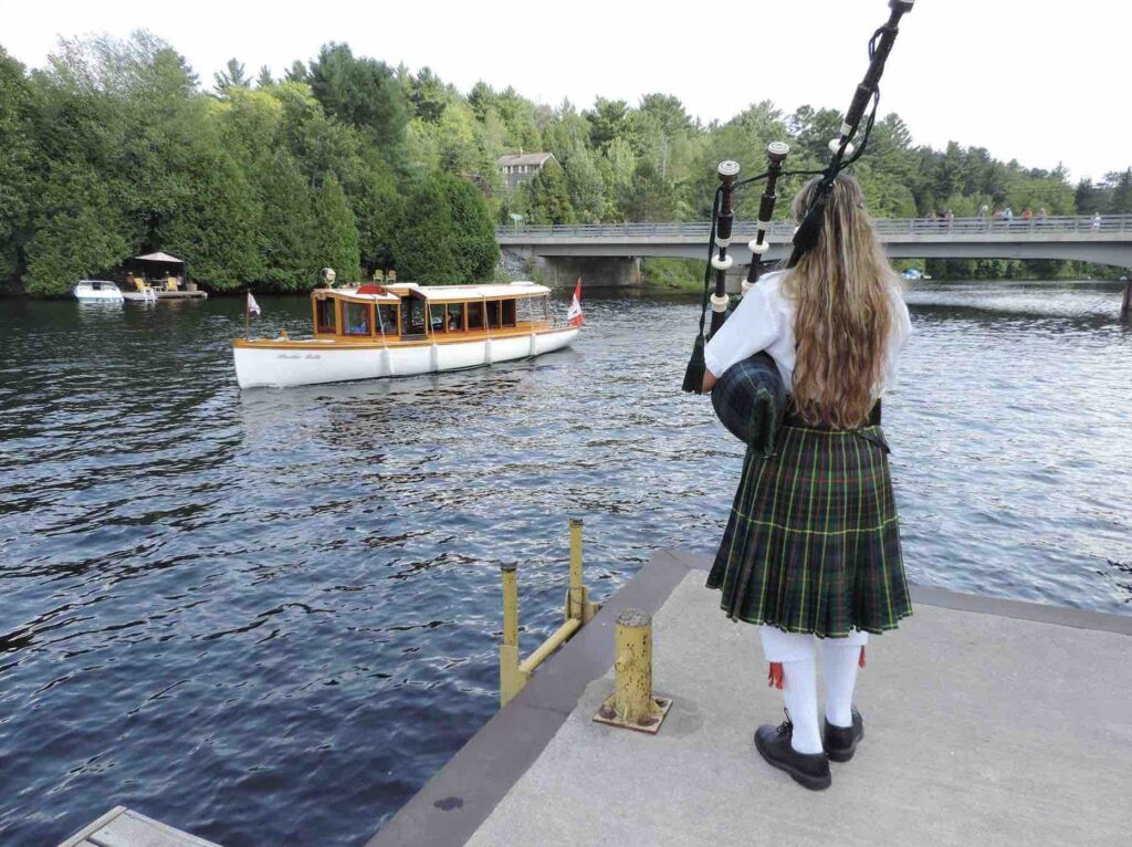 The Marvellous Lake of Bays Antique Boat Show with antique boats and bagpiper on dock
